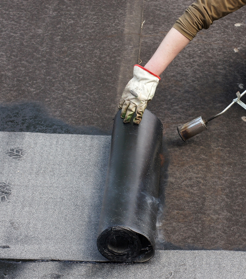 Worker doing roofers welding line with a gas torch